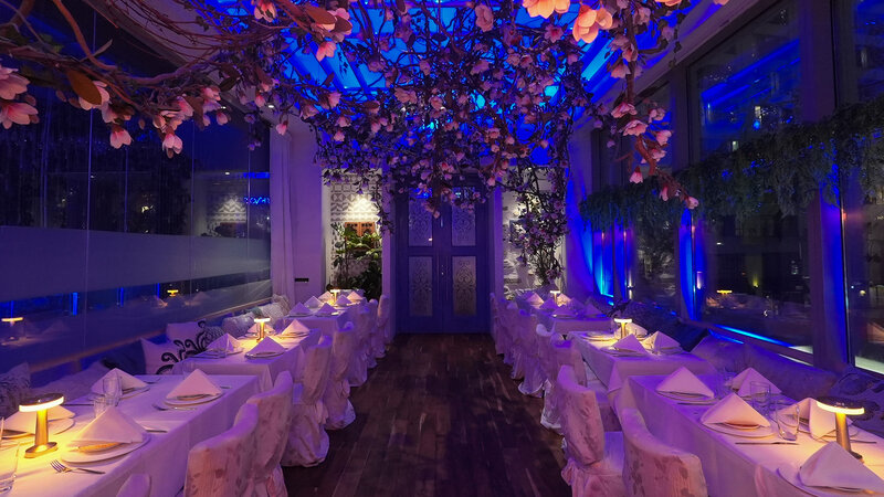 Mykono room at night with long set tables with flower decorations