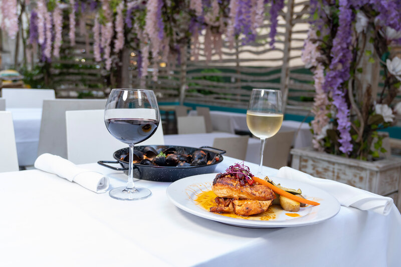 Two entrees with red and white wine on outdoor dining table