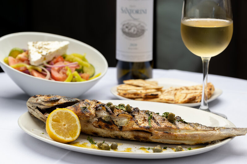 Chilean sea bass entree with side salad, pita bread and glass of white wine