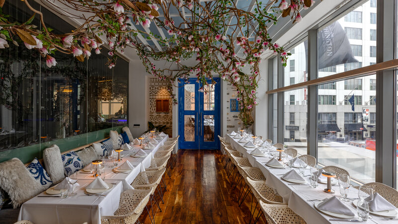 Mykono room during the day and long set tables with flower decorations